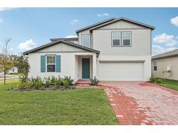 Two-story house with gray siding, teal shutters, and a brick driveway at 4710 Jasmine Ct, Leesburg, FL 34748