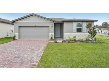 One story home with gray siding, light blue shutters, and a brick paver driveway at 4751 Jasmine Cir, Leesburg, FL 34748
