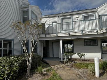 Exterior view of condo building with walkway and landscaping at 2520 Woodgate Blvd # 202, Orlando, FL 32822