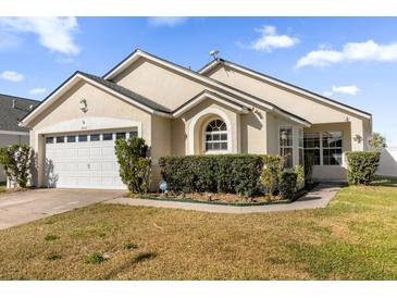 Tan house with a two-car garage and well-manicured lawn at 2660 Oneida Loop, Kissimmee, FL 34747