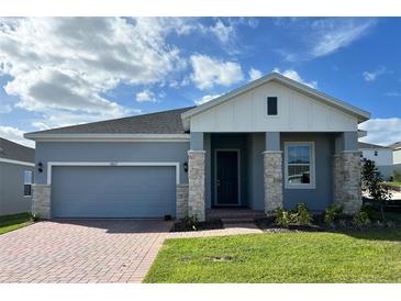 Gray house with white accents, stone facade, and a two-car garage at 6817 Serpent Hawk Lane St, Howey In The Hills, FL 34737