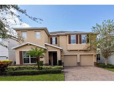 Two-story house with tan siding, three-car garage, and landscaped yard at 9036 Arbors Edge Trl, Windermere, FL 34786