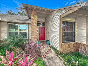 Inviting house exterior featuring a red door and well-manicured landscaping at 1725 Singing Palm Dr, Apopka, FL 32712