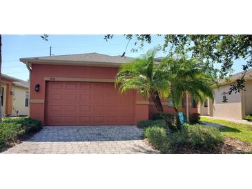 Orange house exterior with a two-car garage and palm trees at 836 Grand Canal Dr, Kissimmee, FL 34759