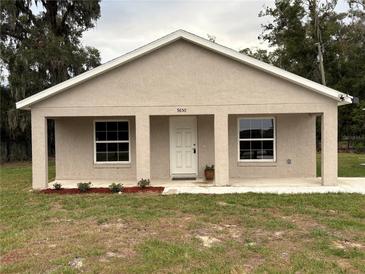 Tan house with white door, covered porch, and landscaping at 9650 Nw Gainesville Rd, Ocala, FL 34475