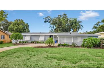 Updated mid-century home with a landscaped lawn and driveway at 3511 Hargill Dr, Orlando, FL 32806