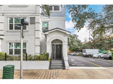 Exterior view of a light gray building with a black door, steps, and landscaping at 204 E South St # 1055, Orlando, FL 32801