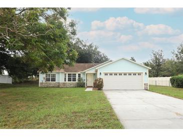 Light blue house with white garage door and stone accents, situated on a grassy lot at 17646 Washington St, Winter Garden, FL 34787