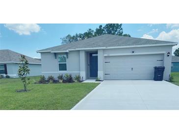 Single-story house with attached garage, landscaping, and driveway at 310 Gardenia Ct, Poinciana, FL 34759