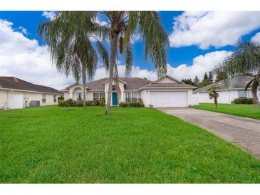 Single-story house with a green lawn, driveway, and palm trees at 577 Sunridge Woods Blvd, Davenport, FL 33837