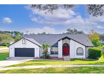 White brick house with red door, dark grey garage door, and landscaped yard at 6639 Canterlea Dr, Orlando, FL 32818