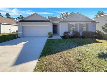 One-story home with gray siding, a two-car garage, and a well-manicured lawn at 127 Hickory Crse, Ocala, FL 34472