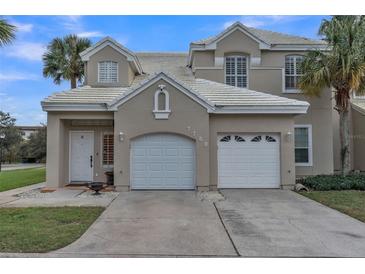 Tan two-story house with white garage doors and landscaping at 7700 Carriage Homes Dr # 4, Orlando, FL 32819