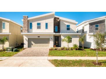 Two-story modern home with neutral colors and a landscaped lawn at 8888 Cabot Cliffs Dr, Kissimmee, FL 34747