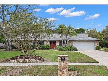 Single-story home with stone facade, red door, and landscaped yard at 369 Forest Park Cir, Longwood, FL 32779