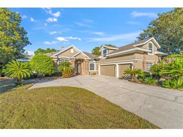 Tan two-story house with three car garage, landscaping, and palm trees at 17429 Cobblestone Ln, Clermont, FL 34711