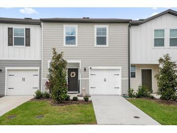 Two-story townhome with gray siding, white accents, and a two-car garage at 397 Madison Dr, Davenport, FL 33837