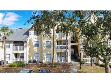 Front view of condo building, featuring a yellow exterior and lush landscaping at 1037 S Hiawassee Rd # 2815, Orlando, FL 32835