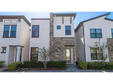 Modern three-story home with stone accents and a landscaped front yard at 172 Villa Domani Cir, Davenport, FL 33896
