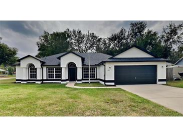 White house with black accents, two-car garage, and grassy lawn at 2921 Hamden St, Deltona, FL 32738