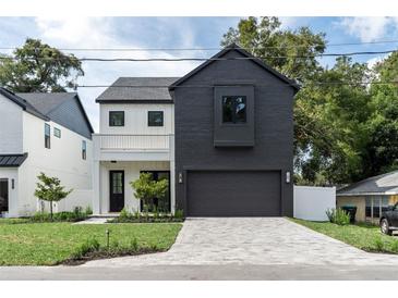 Modern two-story home with black and white exterior, paver driveway, and landscaped yard at 1500 Russell Ave, Orlando, FL 32806