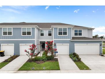 Two-story townhome with gray siding, two-car garage, and landscaping at 2570 Winsome Way, Davenport, FL 33896