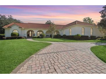 Spanish style home with red tile roof, lush landscaping, and a paved driveway at 1000 Dunhurst Ct, Longwood, FL 32779