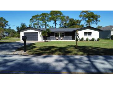 Newly renovated home with modern facade, dark gray garage door, and manicured lawn at 12617 Pine Island Dr, Leesburg, FL 34788