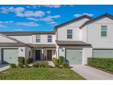 Two-story townhome with light-colored siding, attached garage, and landscaping at 1592 Wynford Cir, Tavares, FL 32778