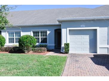 Well-maintained light blue house with a two-car garage and neatly landscaped lawn at 2825 Attwater Loop, Winter Haven, FL 33884