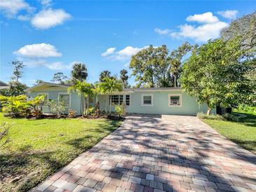 Light blue house with a brick driveway, landscaping, and lush green lawn at 2410 Sanford Ave, Sanford, FL 32771