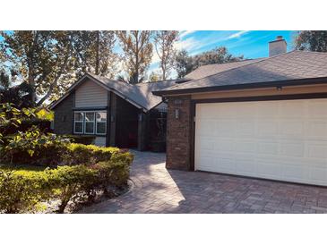 Brick house with a large white garage door and well-manicured landscaping at 6850 Spring Rain Dr, Orlando, FL 32819