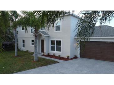 Two-story house with gray siding, brown garage door, and palm trees at 1115 Munster Ct, Kissimmee, FL 34759