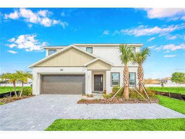 Two-story house with a gray and beige exterior, a brown garage door, and a paved driveway at 4481 Monado Dr, Kissimmee, FL 34746