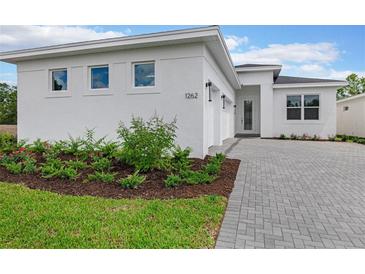 White modern house with a paver driveway and landscaping at 1262 Venice Ct, Deland, FL 32724