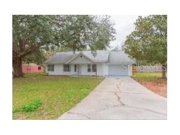 White single story home with a green lawn and driveway at 4 Cedar Trace Way, Ocala, FL 34472