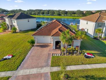 Single-Gathering home with solar panels and a brick driveway, located on a lake at 1651 Kingfisher Ct, Kissimmee, FL 34746