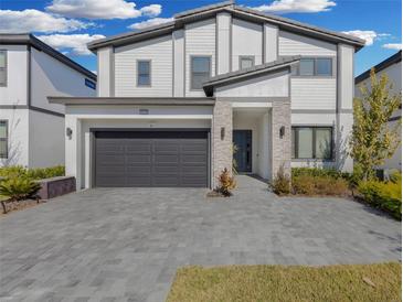 Two-story home with gray stone and white siding, dark garage door, and landscaped yard at 6133 High Seas Dr, Orlando, FL 32821