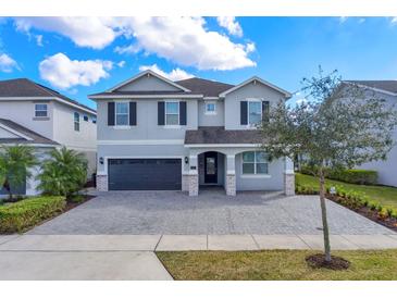 Two-story house with gray siding, dark gray garage doors, and a paved driveway at 7457 Marker Ave, Kissimmee, FL 34747