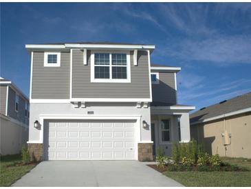 Two-story house with gray siding, white garage door, and landscaping at 2306 Amorie Dr, Kissimmee, FL 34746