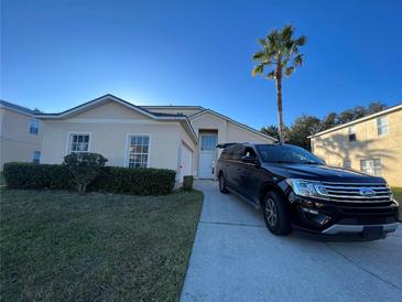 Two-story house with attached garage and a spacious driveway, surrounded by manicured landscaping at 612 Bloomingdale Dr, Davenport, FL 33897
