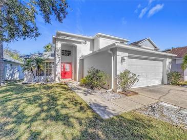 Two-story house with red door, attached garage, and landscaped yard at 10935 Rushwood Way, Clermont, FL 34714