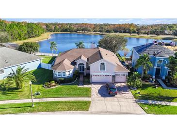 Aerial view of two-story house near lake, showcasing landscaping and neighborhood at 10642 Cloudview Dr, Orlando, FL 32825