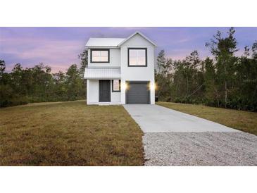 Two-story house with gray metal roof and gray garage door, sits on a grassy lot at 765 6Th Ave, Osteen, FL 32764