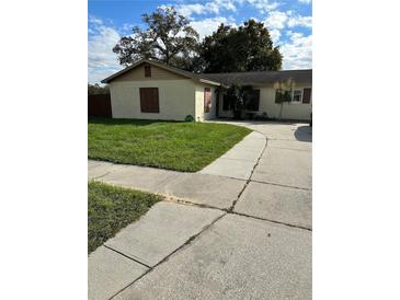Tan house with brown shutters, well-maintained lawn, and a paved driveway at 2902 Calumet Dr, Orlando, FL 32810