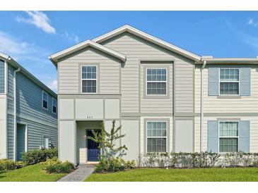 Two-story house with gray siding, blue door, and landscaping at 866 Paradise Dr, Davenport, FL 33897