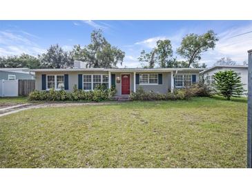 Ranch style home with red door, landscaping, and a spacious lawn at 1944 Bering Ave, Winter Park, FL 32789