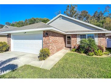 Brick ranch home with a two-car garage and landscaped lawn at 548 Coral Trace Blvd, Edgewater, FL 32132