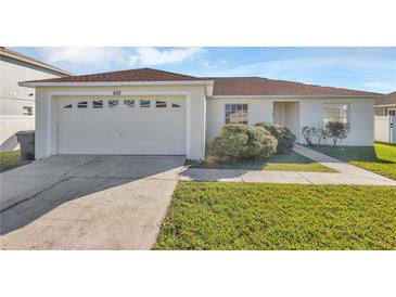 Single-story house with a two-car garage and a well-maintained lawn at 610 Crane Dr, Poinciana, FL 34759