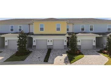 Three-unit townhome building with attached garages and landscaped grounds at 856 Driving Range Ct, Reunion, FL 34747